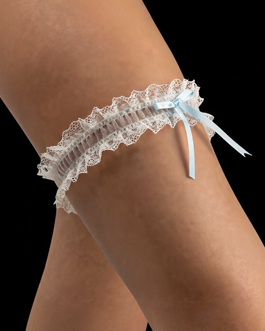 Ariel white bridal garter with lace on both edges and a blue bow, black background